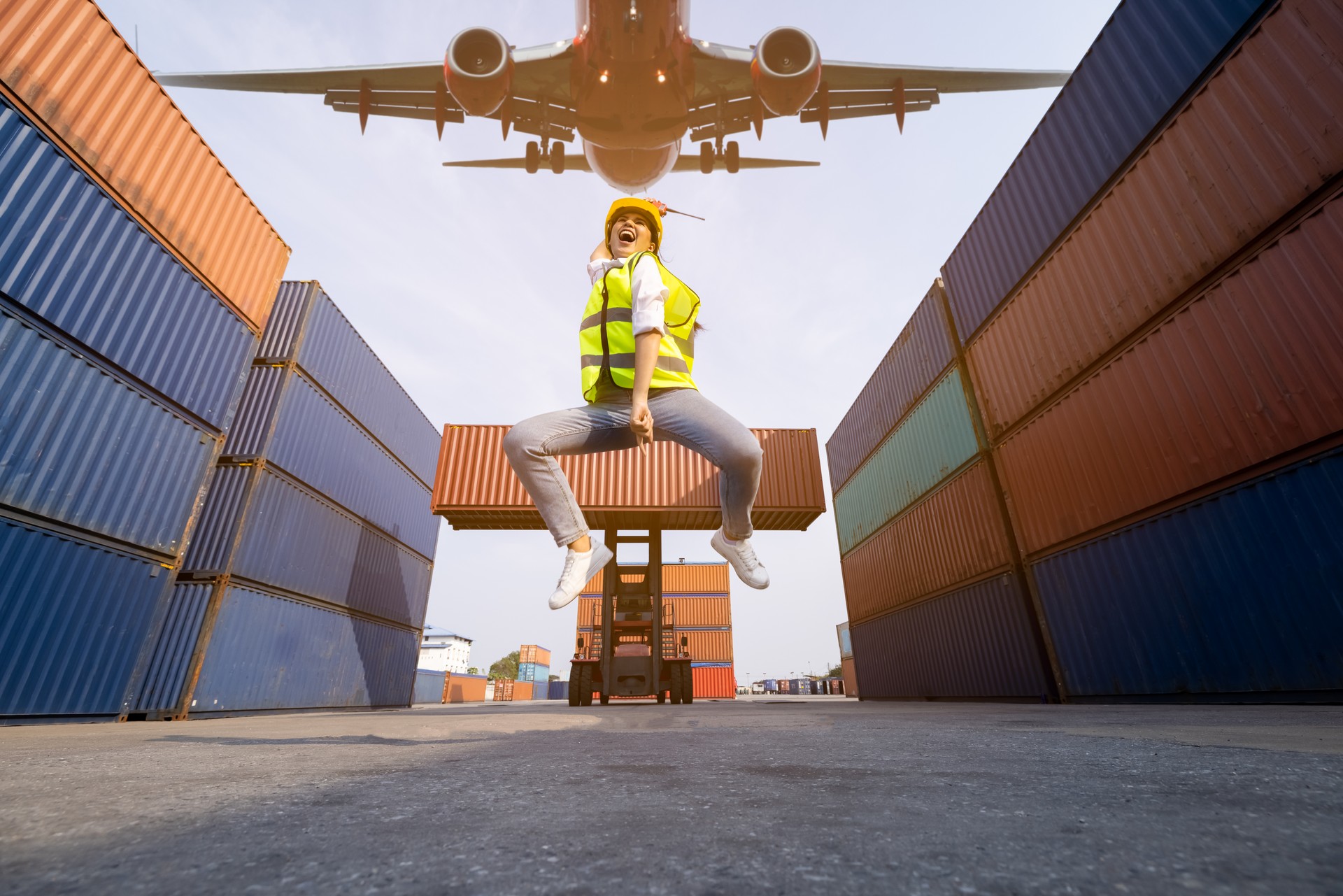 Young asian women foreman  jumping over in work area warehouse container and air plane background . happy summer holiday concept